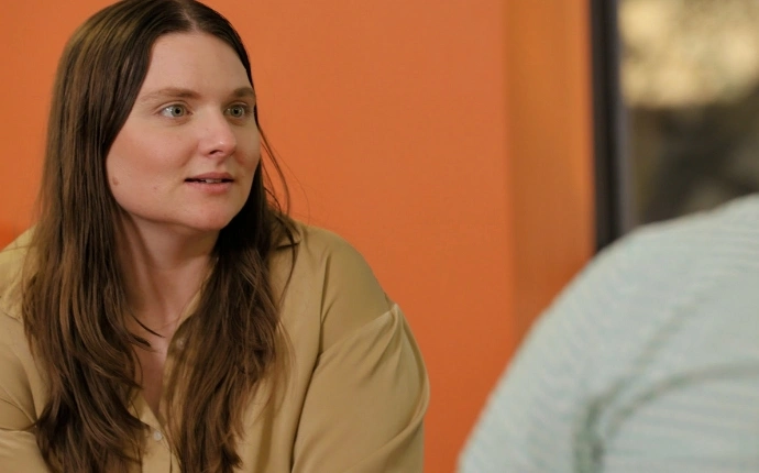 Member of the OuterBox healthcare marketing agency team in a tan shirt against a bright orange backdrop.