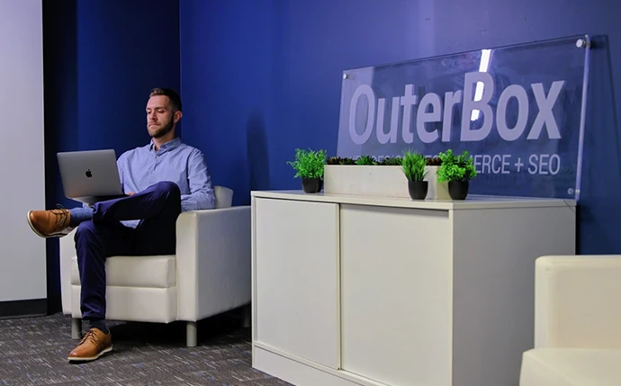 Man working on a website seo audit service in a modern office with OuterBox signage visible
