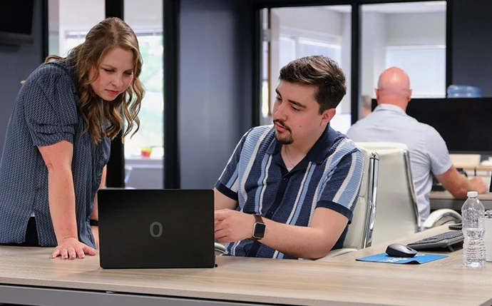 Two OuterBox colleagues reviewing B2B SEO solutions on a laptop together in the OuterBox office