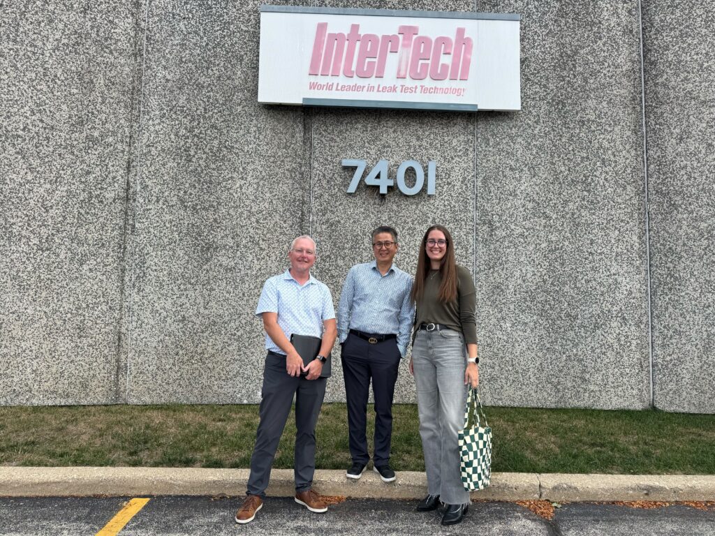 Three people stand outside the InterTech building during an OuterBox client visit.